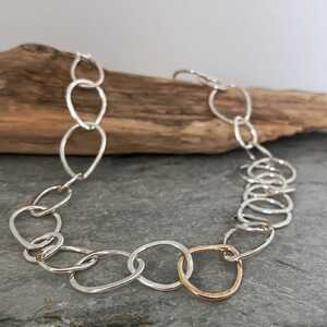 This is a picture of a silver chain necklace with one gold central link