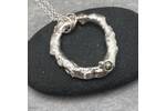 Organic silver circle pendant with a green sapphire