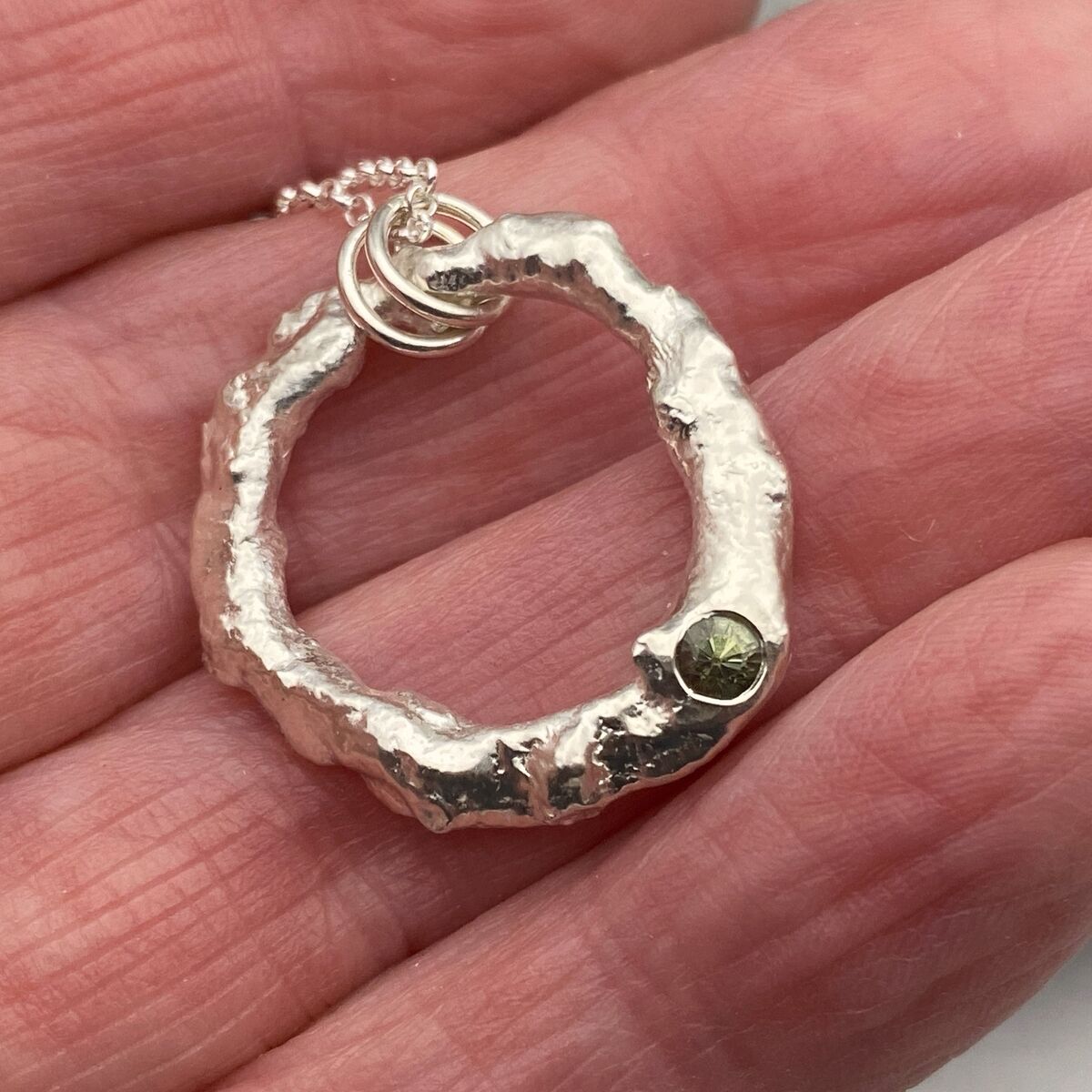 Organic silver circle pendant with a green sapphire 2 Organic silver circle pendant with a green sapphire 2