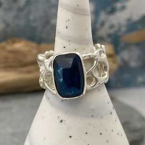 This is a picture of a silver open work ring with a teal blue gemstone