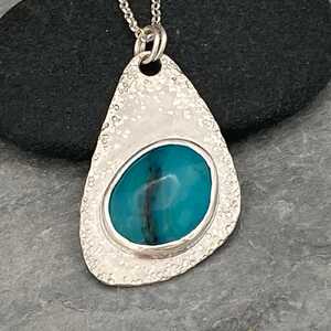 This is a picture of a silver pendant with a blue gemstone