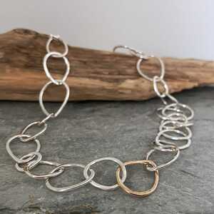 This is a picture of a silver chain necklace with one gold central link This is a picture of a silver chain necklace with one gold central link